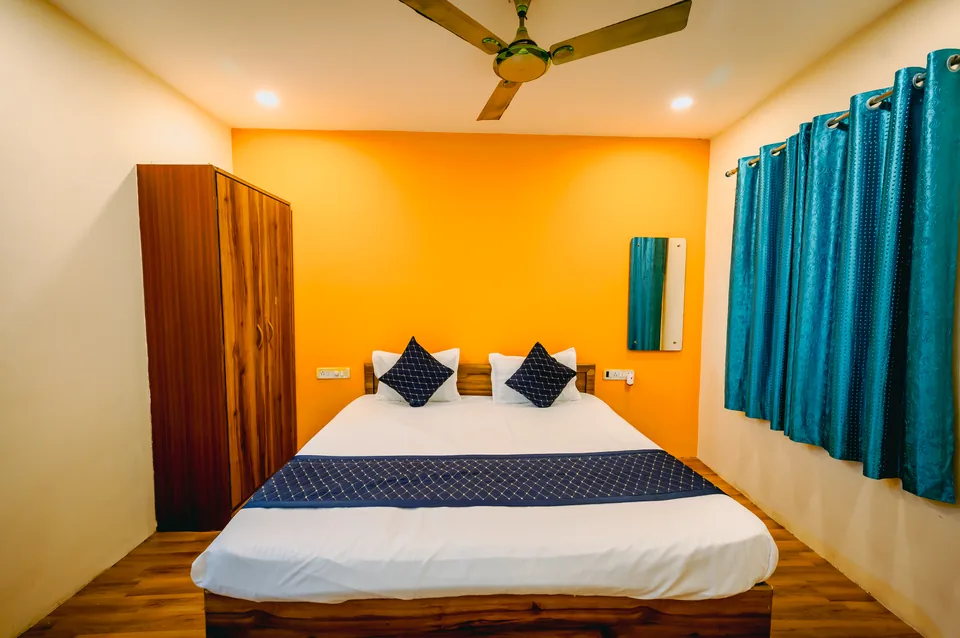 Standard AC Room bed with reading lamp and curtained window